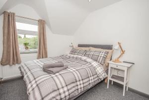 a bedroom with a bed with a plaid blanket and a window at Featherbed Cottage in Coventry