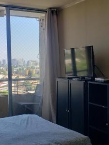 聖地亞哥的住宿－Suit vista despejada，一间卧室设有一张床、一台电视和一个窗口。