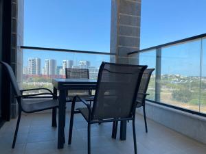 a table and chairs on a balcony with a view of a city at New- Luxury Glil Yam For Family 4 Rooms Parking in Herzliya