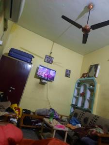 ein Wohnzimmer mit einem Deckenventilator und einem Flachbild-TV in der Unterkunft Vrindavan Home Stay,Varanasi. in Varanasi