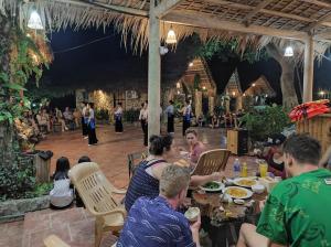 a group of people sitting at a table in a restaurant at Le Pont Mu Waterfall Homestay in Ải Hạ