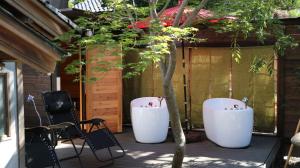 two white tubs sitting next to a tree on a patio at GLOCE 射水 禅楽 築150年の古民家でプライベートサウナ体験 in Shimminato