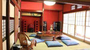 a room with a table and chairs and red walls at GLOCE 射水 禅楽 築150年の古民家でプライベートサウナ体験 in Imizu
