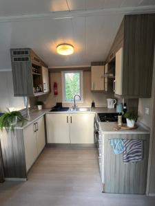 a kitchen with white cabinets and a sink at Ruim Chalet, midden in het bos! in Nunspeet