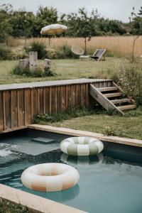 uma piscina com duas cadeiras insufláveis na água em Maison d'hôtes Bel Estiu em Saint-Geniès