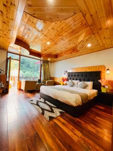 um quarto com uma cama grande e um tecto em madeira em Himalayan Riverside Resort, Manali em Manali