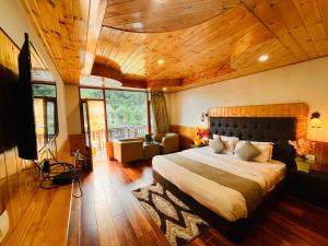 Un dormitorio con una cama grande en una habitación con techos de madera. en Himalayan Riverside Resort, Manali en Manāli