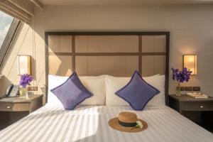 um chapéu em cima de uma cama com almofadas roxas em Boulevard Hotel Bangkok Sukhumvit em Banguecoque