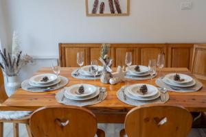 a wooden table with plates and wine glasses on it at Apartmaji Ježek Kope in Šmartno pri Slovenj Gradcu
