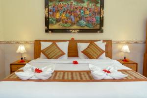 - une chambre dotée d'un lit avec des draps blancs et des archets rouges dans l'établissement Puri Prana Guest House, à Ubud