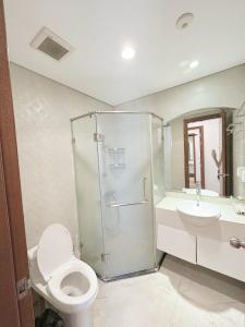 y baño con ducha, aseo y lavamanos. en Vinhomes Times City 1BR, en Hanói