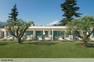 a building with chairs and trees in the grass at Seven Park Hotel Lake Como - Adults Only in Colico