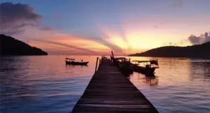 a dock with boats on the water at sunset at Big Head Bungalows in Koh Rong Sanloem +9 photos