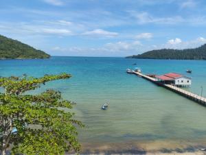 a dock in the water with a boat in the water at Big Head Bungalows in Koh Rong Sanloem