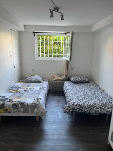 2 camas en una habitación con ventana en Appartement T3 avec accès jardin a 20 minutes de la Gare, en Juvisy-sur-Orge