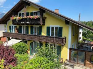 ein gelbes Haus mit grünen Fensterläden und Blumenkästen in der Unterkunft Haus Schmidhuber Wohnung 1 in Grossgmain