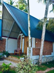 a brick house with a blue roof and two palm trees at Steps Garden Resort in Negombo