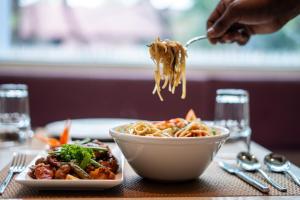 a person is eating noodles from a bowl of food at Lilac Hotel Guruvayur in Guruvāyūr