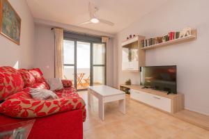 sala de estar con sofá rojo y TV de pantalla plana en Paraiso Costero - Adults Only - en Conil de la Frontera