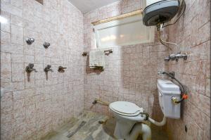 a bathroom with a toilet and a window at FabHotel Monalisa in Manāli