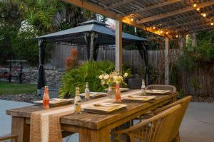 una mesa de madera con sillas y una sombrilla en Traveler's Dream SD Pool Home Game Room, en San Diego