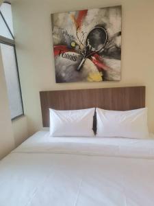 SCC Hotel Chinatown في كوالالمبور: غرفة نوم مع سرير مع لوحة على الحائط بمضرب التنس