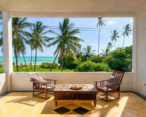 a room with a table and chairs and a view of the ocean at Kholle Villa in Jambiani