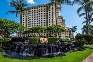 a fountain in front of a building with palm trees at Ko Olina Beach Villas B602 in Kapolei