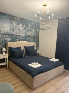 a bedroom with a bed with blue sheets and a chandelier at Sandanski Apartments Top Center in Sandanski