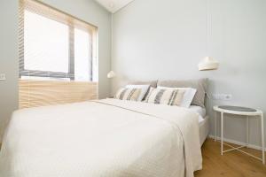 um quarto branco com uma cama grande e uma janela em Vanagupes Park Apartment, By Cohost em Palanga