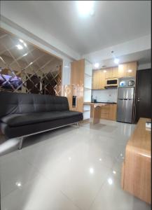 ein Wohnzimmer mit einem schwarzen Sofa und einer Küche in der Unterkunft Apartment TransPark Cibubur, TSM in Kalimanggis
