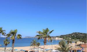 Blick auf einen Strand mit Palmen und das Meer in der Unterkunft GASMIM29 - Golfe de St-Tropez, chalet climatisé dans domaine arboré in Gassin