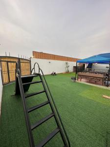 um parque infantil com uma escada num quintal com uma tenda em استراحة رفييف em Khalij Salman
