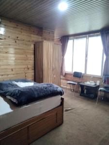 een slaapkamer met een bed in een kamer met houten wanden bij View Point Residency , Darjeeling in Darjeeling