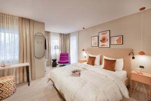 a hotel room with a large bed and a purple chair at Boutique Hotel Am Park in Valdaora