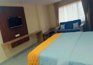Habitación de hotel con cama grande y TV en Urban Lounge, en Rajahmundry