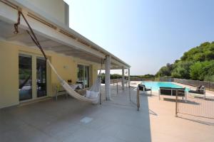 a patio with a hammock and a swimming pool at Salicornia - Sea view villa with pool in Marsala
