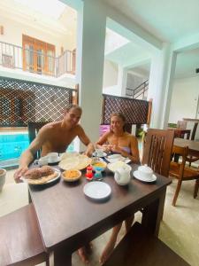 mężczyzna i kobieta siedzący przy stole z jedzeniem w obiekcie Bienvenido Cozy Marker w mieście Matara
