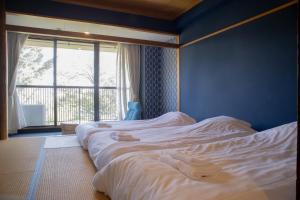 a bedroom with two white beds and a window at ISOLA Izukogen in Ito