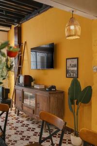 uma sala de estar com televisão numa parede amarela em Ben Thanh Vietnamese cultural house by SSens Homes em Ho Chi Minh