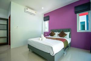 um quarto com uma cama com uma parede roxa em บ้านพักชายคลอง @บางปู สามร้อยยอด em Ban Bang Pu