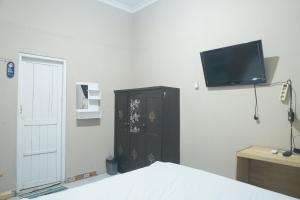 a bedroom with a bed and a tv on the wall at OYO 93654 Gr Kost Kaladan in Rantau