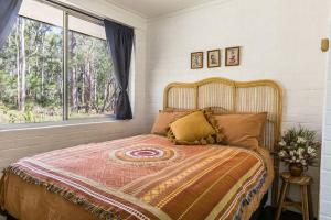 um quarto com uma cama grande e uma janela em Bushy Sleeps - Eco Friendly Tranquil Escape em Gnarabup