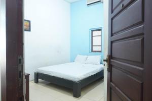 a small bedroom with a bed and a door at OYO 93654 Gr Kost Kaladan in Rantau