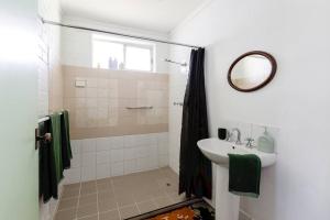 uma casa de banho com um lavatório e um chuveiro com um espelho. em Bushy Sleeps - Eco Friendly Tranquil Escape em Gnarabup
