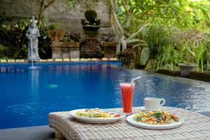 - une table avec deux assiettes de nourriture et une boisson dans l'établissement Puri Prana Guest House, à Ubud