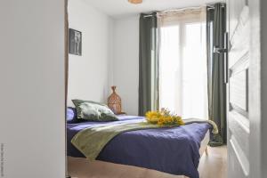 - une chambre avec un lit doté de draps bleus et une fenêtre dans l'établissement T3, Balcons, cœur de Marseille, à Marseille