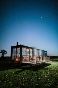 a glass house sitting in a field at night at the BOX BNB in Wilton