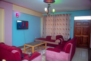a living room with red chairs and a table at Balozi Luxury Homes in Nanyuki
