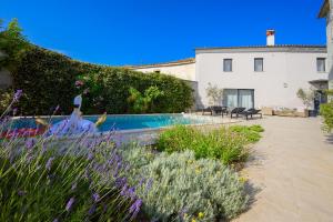 a garden with purple flowers in front of a house at VILLA LATINI - Ideal for a family vacation. Heated pool. Local breakfast optional available in Svetvinčenat
